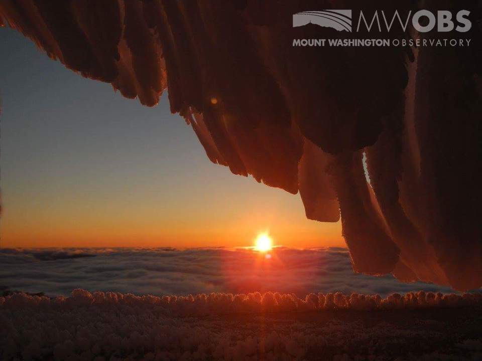 Sun setting into a sea of undercast with rime ice in the foreground